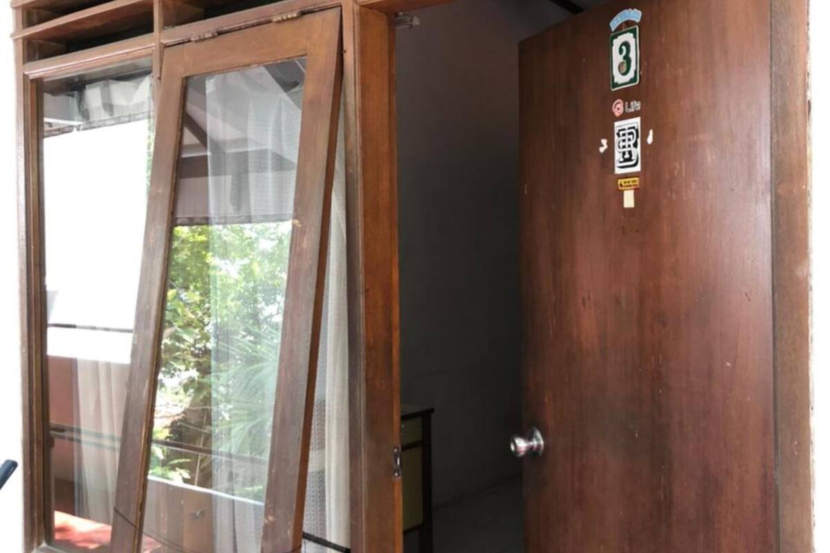 A wooden door with a window, a metal handle, and a sticker with a number and Chinese characters.