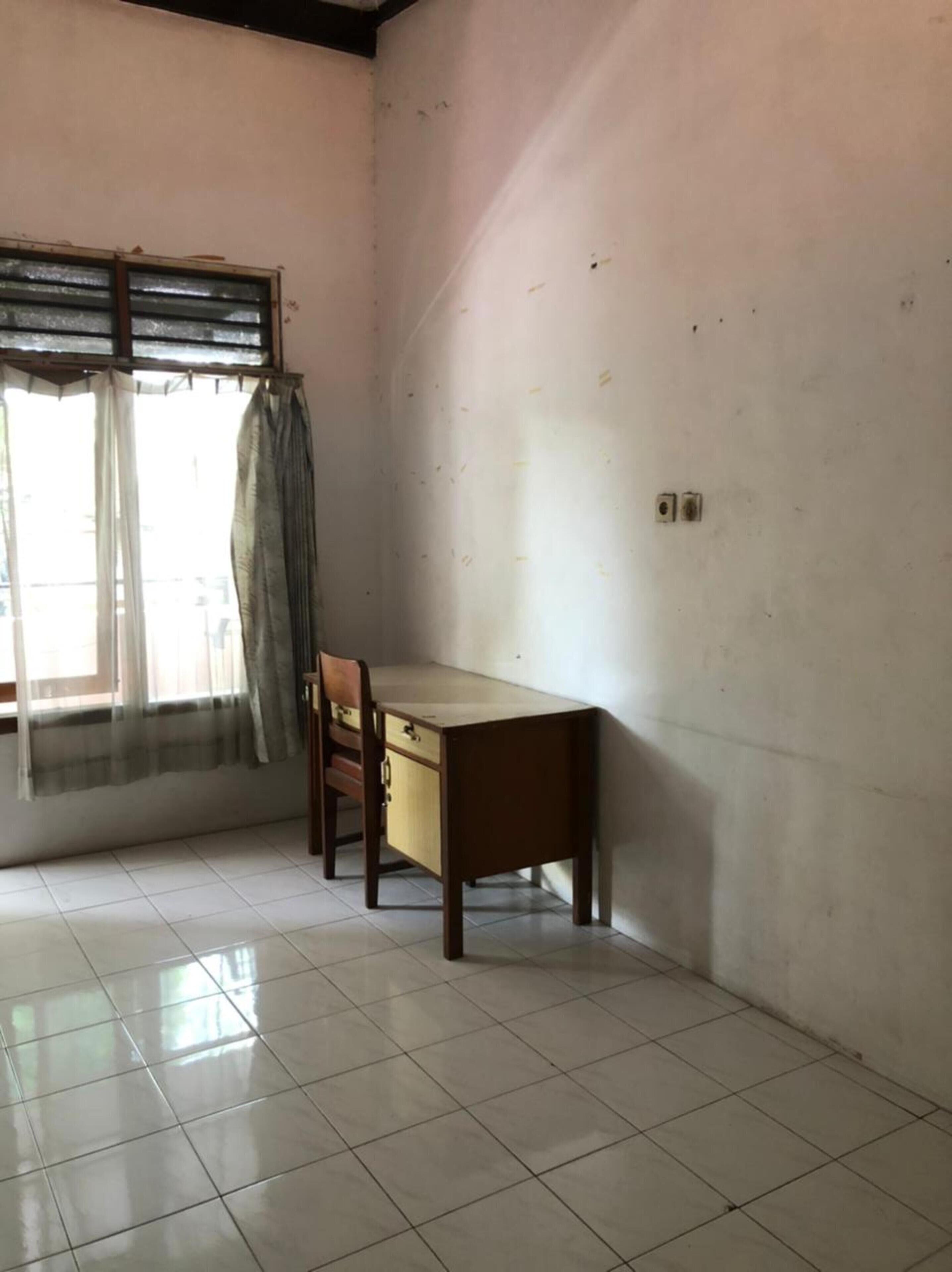 Une pièce avec un bureau en bois, une chaise et une fenêtre avec des rideaux.
