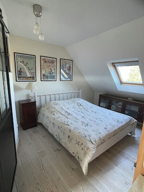 Una camera da letto con un letto, un comodino, una cassettiera e un lucernario.