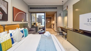 Quarto de hotel moderno com uma cama grande, uma escrivaninha e vista para a sala de estar.