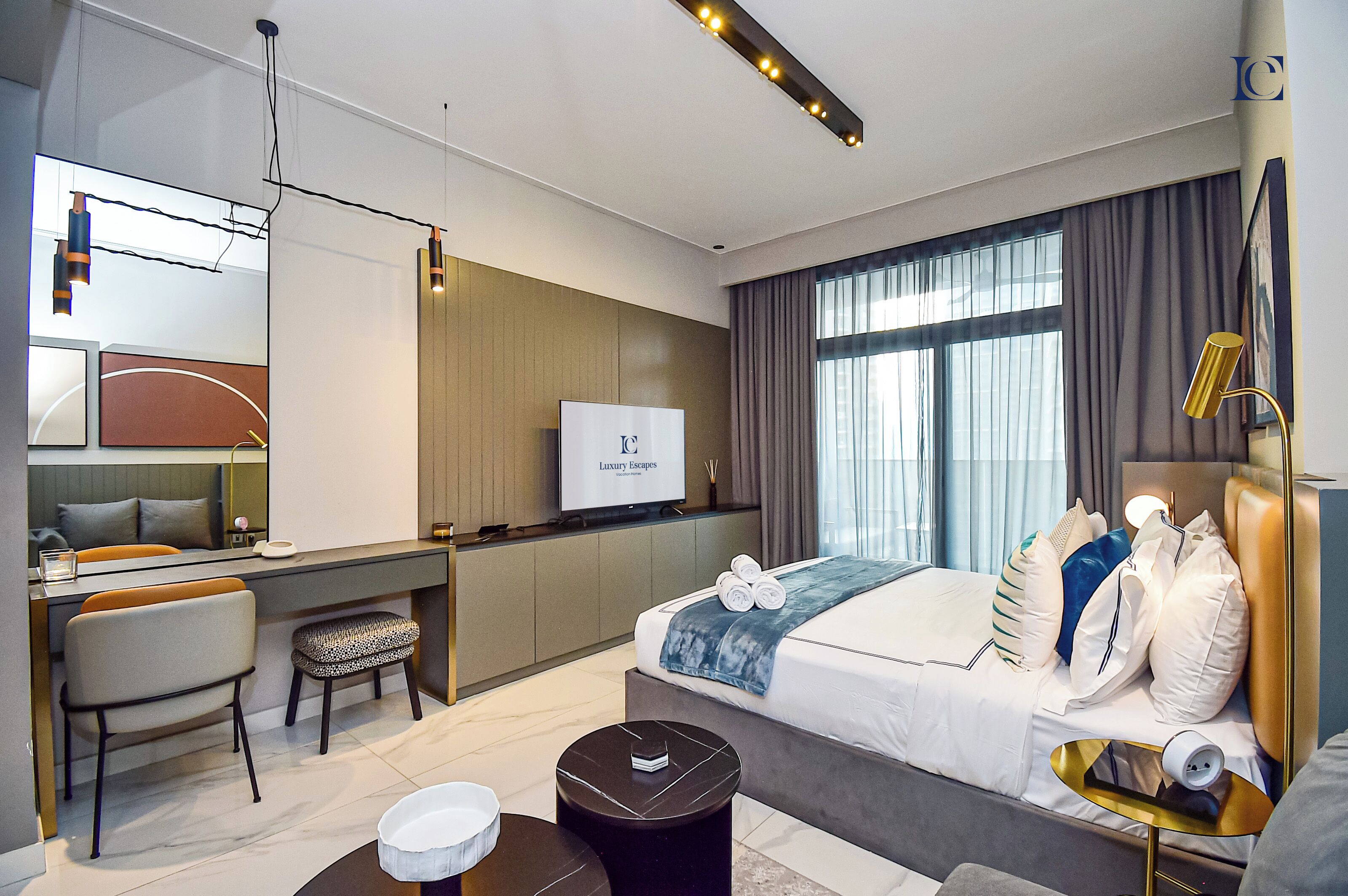 Et moderne hotelværelse med seng, skrivebord, stol og et fjernsyn, der viser "Luxury Escapes".