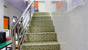Un escalier orné de carreaux décoratifs mène à une pièce où se trouvent un lit et un bureau.