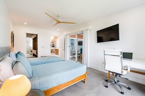 Relax in a serene space with a large bed, flat-screen TV, and sliding glass door leading to an outdoor area.