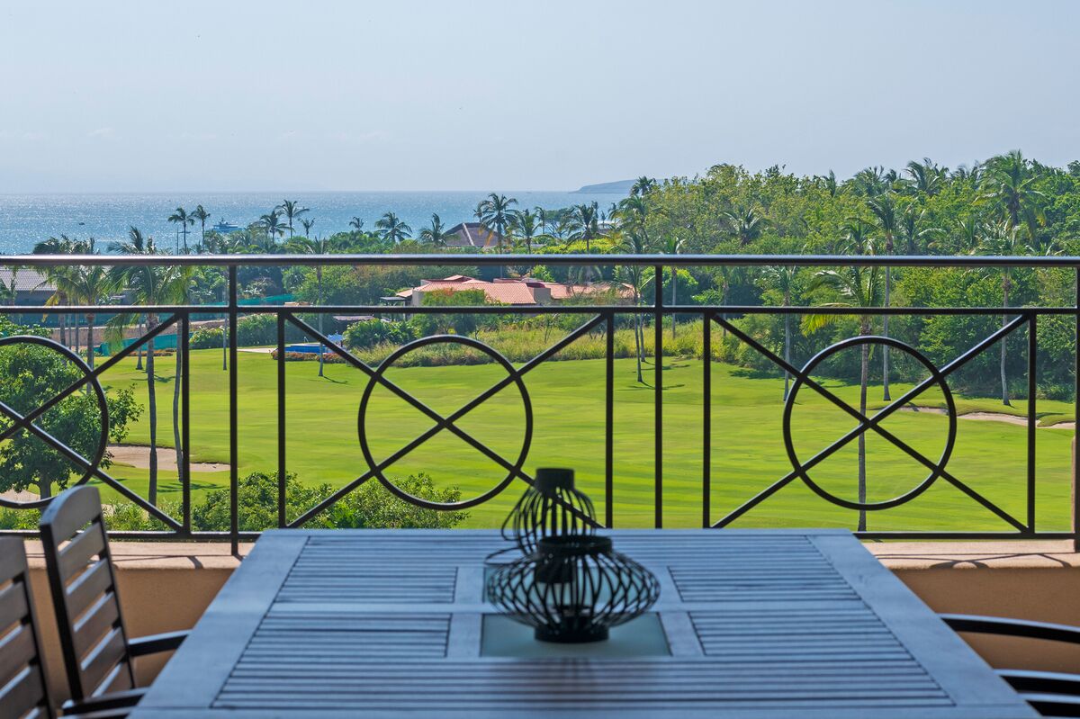 A balcony with a view of a golf course and the ocean.