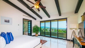 A modern bedroom with a large bed, a ceiling fan, a potted plant, and a view of the outdoors. - Beautiful 3 Bedroom Condo (Punta de Mita)