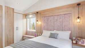 Una camera da letto con un letto grande, armadio a muro, comodini, una finestra con vista e un punto luce a parete.