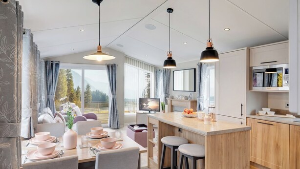 Una cucina moderna con mobili in legno, un'isola centrale, sgabelli da bar e luci a sospensione.