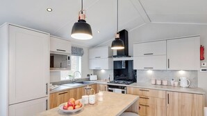 Una cucina moderna con mobili bianchi, un'isola centrale con sgabelli, un piano cottura a gas e luci a sospensione.