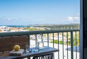 A balcony with a wooden table, a lemon, and a bottle of water.