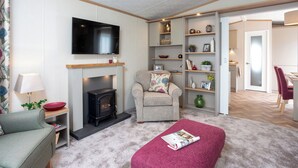 A living room with a fireplace, sofa, armchair, and a television.