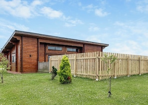 A wooden cabin with a fenced yard, a small tree, and a clear sky. - 2 bedroom accommodation in Withernsea (Withernsea)