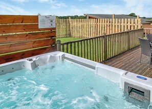 A hot tub with a wooden deck and a wooden fence in the background. - 2 bedroom accommodation in Withernsea (Withernsea)