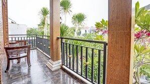 A balcony with a tiled floor, wooden chairs, and a railing.