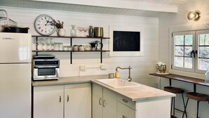 A modern kitchen with a central island, built-in oven, and a ceiling fan. - Little Olive Eco Cabin on a private dam.. Perfect for a relaxing weekend away! (Parklands)