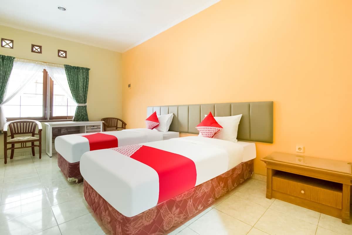 Une chambre d’hôtel avec deux lits, un bureau et une chaise.