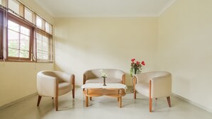 Een kamer met drie fauteuils, een salontafel en een bloemenvaas.
