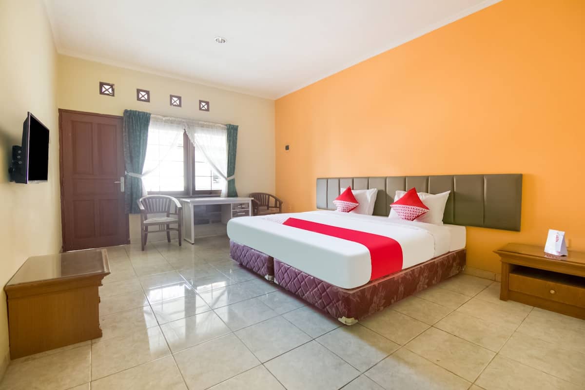 Une chambre d’hôtel avec un grand lit, un bureau, une chaise et un téléviseur fixé au mur.