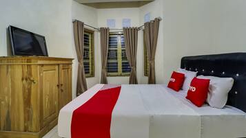 A neatly arranged bedroom with a bed, a wooden wardrobe, and a television on a stand.