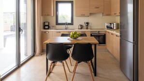 Een moderne keuken met houten kastjes, een roestvrijstalen koelkast en een eettafel met zwarte stoelen.
