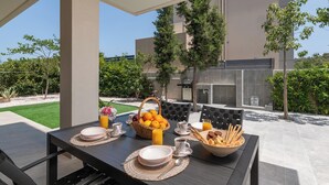 Een buiten eethoek met een ontbijttafel, compleet met borden, bekers en een schaal met broodstengels.