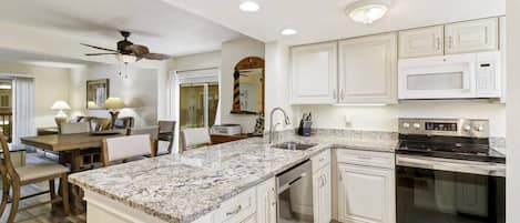 A kitchen with white cabinetry, a granite countertop, a built-in oven, and a ceiling fan.