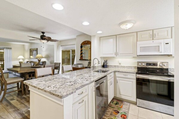 A kitchen with white cabinetry, a granite countertop, a built-in oven, and a ceiling fan.