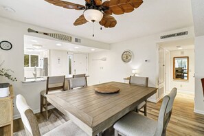 A dining area with a wooden table, chairs, a ceiling fan, and a clock on the wall. - 302 Tanglewood Villa (Hilton Head Island)