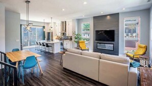 Un salon moderne comprenant un canapé, des fauteuils, une table à manger et un coin cuisine.