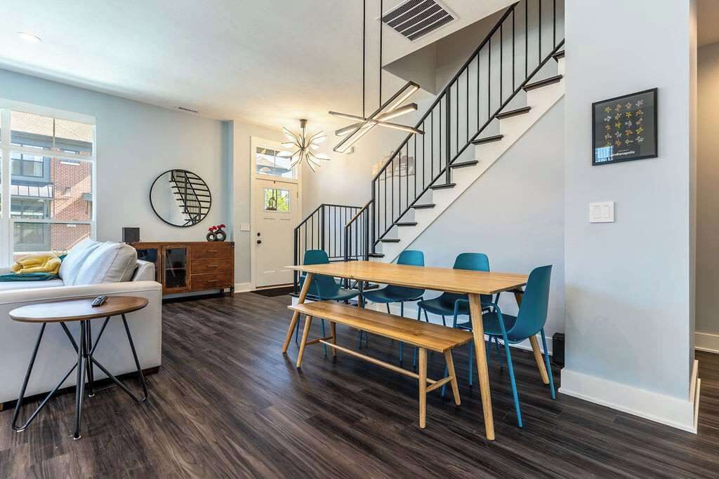 A modern living room with a dining area, a staircase, and a view of the outside.