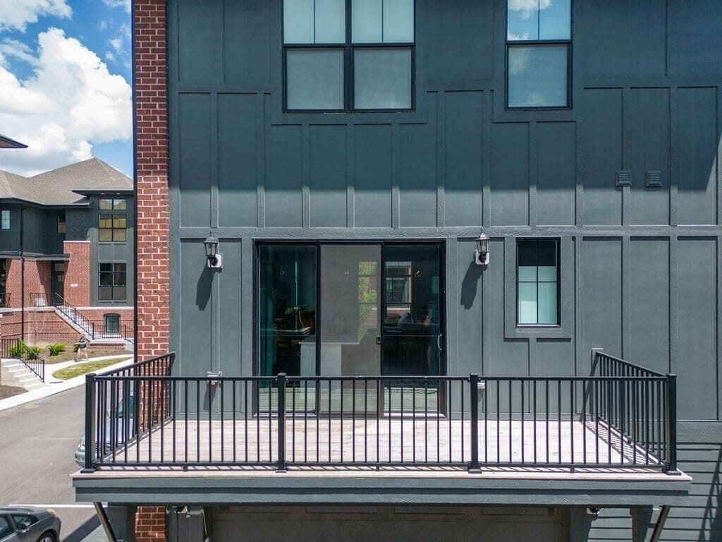 Un bâtiment moderne à la façade grise, doté d’un balcon avec une rambarde noire et d’une entrée bien visible.