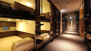 A train car with bunk beds, each labeled with a number, and a control panel on the left. - Acro Capsule Hotel Namba Dotonbori (Osaka)