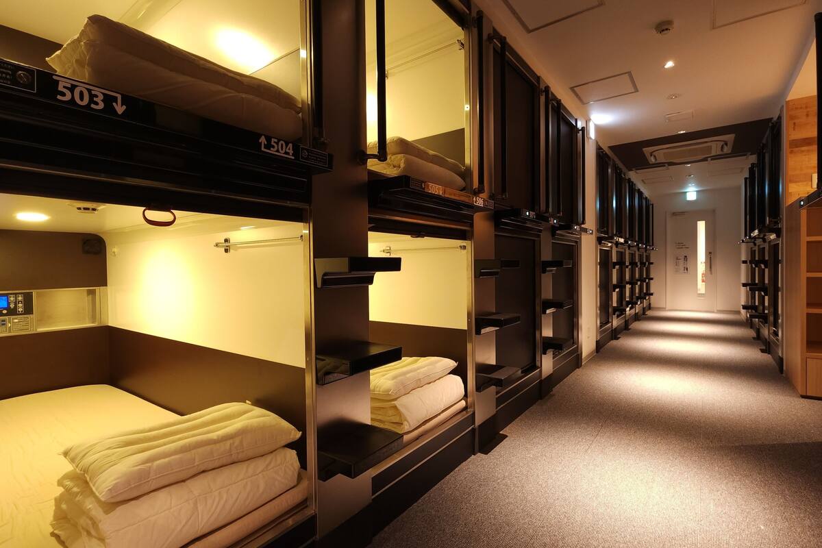 A train car with bunk beds, each labeled with a number, and a control panel on the left.