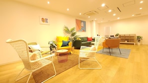 A modern living room with wicker chairs, a yellow sofa, and a green couch. - Acro Capsule Hotel Namba Dotonbori (Osaka)