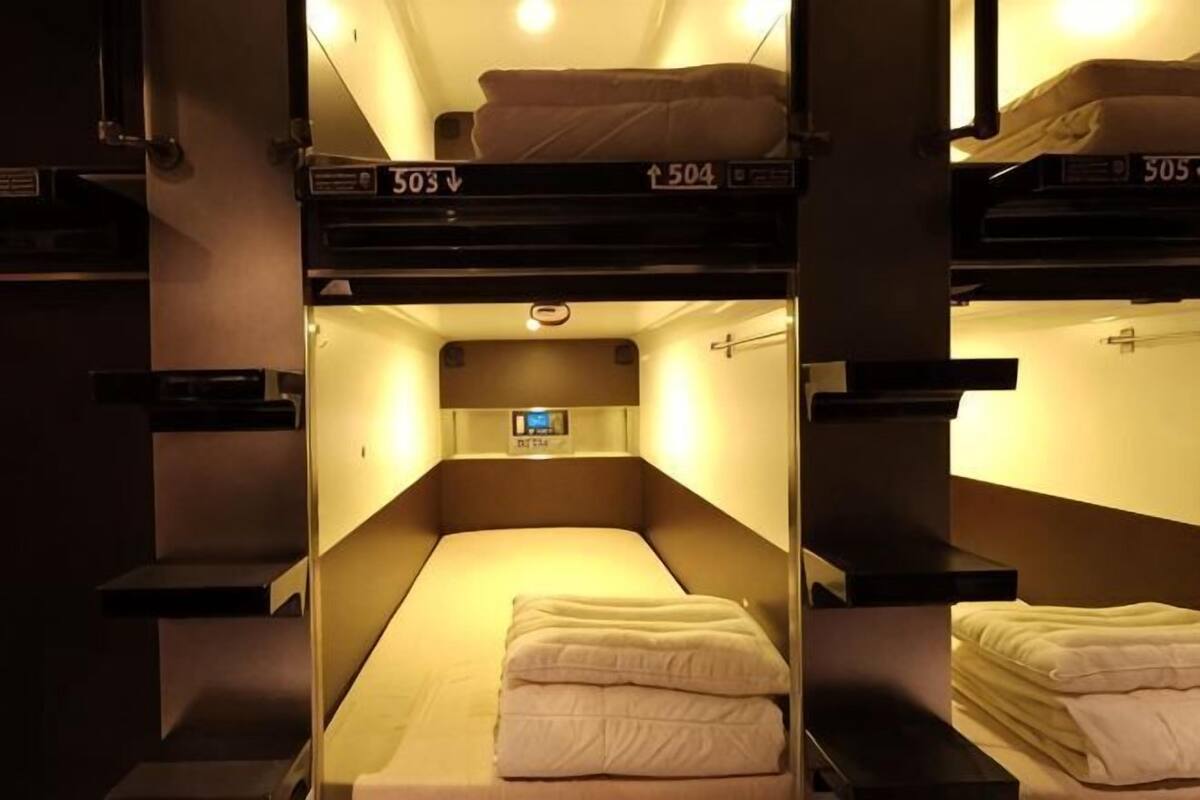 A train compartment with bunk beds, each bed marked with a number, and a small digital clock above the beds.