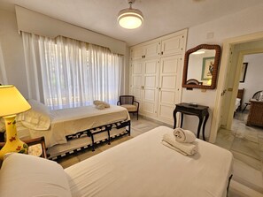 A hotel room with a bed, a chair, a desk, a lamp, and a wardrobe.