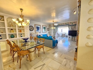 A spacious living area with a dining table, chairs, a sofa, and a television.