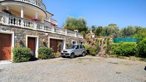 A stone building with a car parked in front, a balcony with flowers, and a clear sky. - Holiday Apartment "Villa Isabella Casa Lucia" with Sea View, Shared Terrace & Wi-Fi (Imperia)