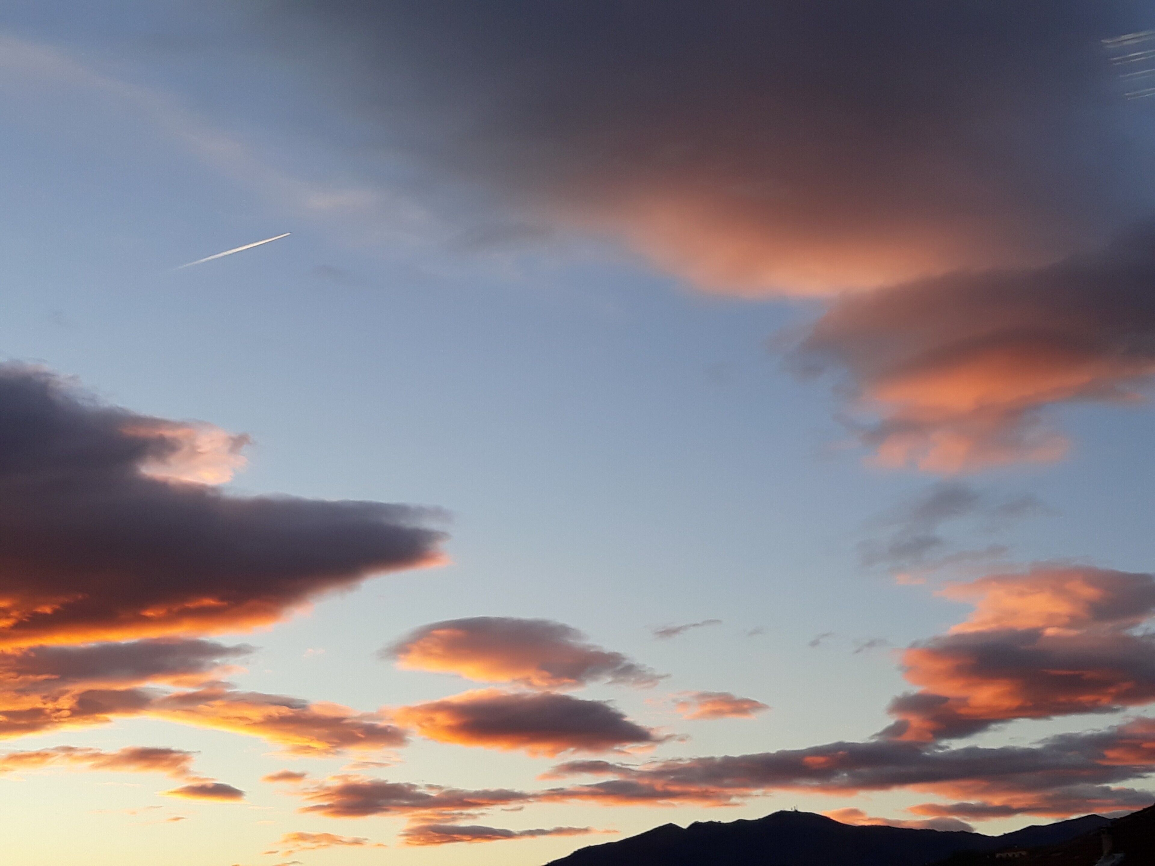 Klarer Himmel mit Wolken und einem entfernten Gebirge.