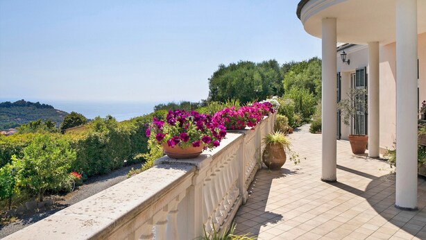 A balcony with a view of the sea, a potted plant, and a building with columns. - Holiday Apartment "Villa Isabella Casa Lucia" with Sea View, Shared Terrace & Wi-Fi (Imperia)