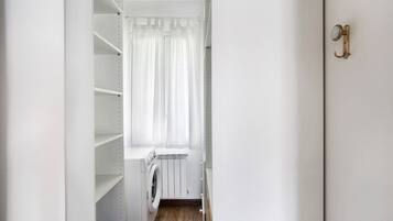 Een wasserette met een wasmachine, een droogrek en een radiator.
