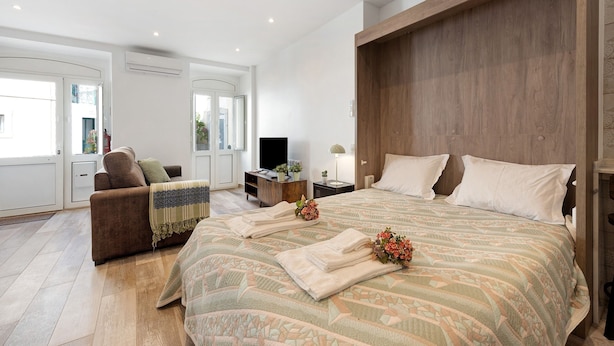 A spacious bedroom with a large bed, a sofa, a TV, and a desk.
