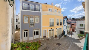 A narrow street with colorful buildings, a cobblestone path, and a person walking.