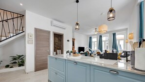Une cuisine moderne avec des meubles bleu clair, un plan de travail blanc et des luminaires suspendus.