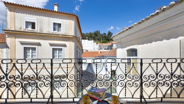 Un balcon avec une table, deux chaises, un livre et deux tasses.
