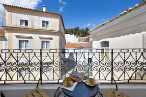 Uma varanda com mesa, duas cadeiras, um livro e duas chávenas.