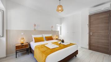 A modern bedroom with a large bed, bedside lamps, a wooden wardrobe, and a hanging light fixture.