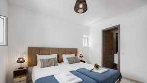 Un lit double avec deux oreillers, une table de chevet avec une lampe et une armoire en bois.