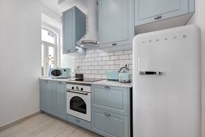 Uma cozinha com armários azul claro, uma geladeira branca, um fogão e um micro-ondas.