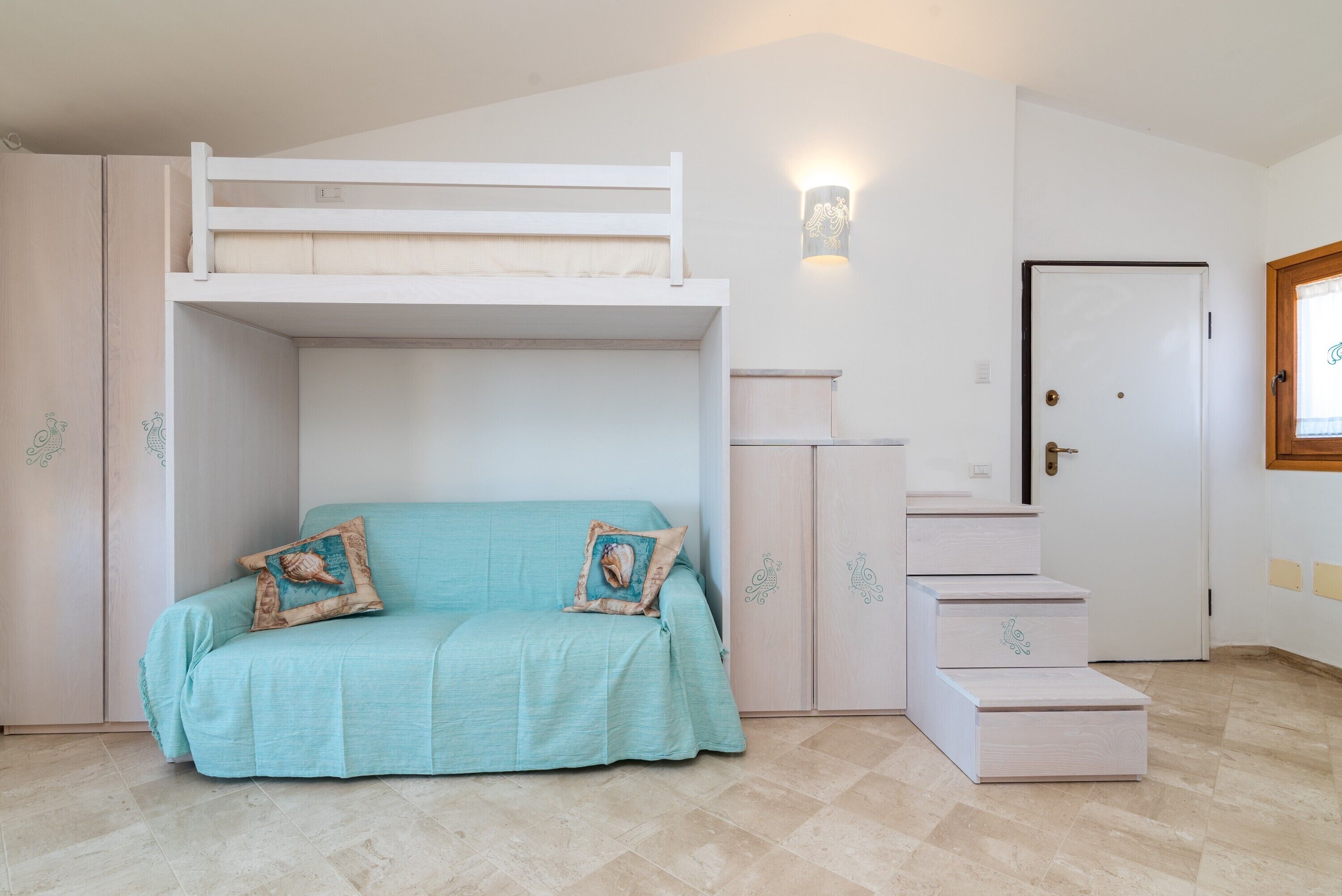 A bunk bed with a sofa, a wardrobe, a door, and a light fixture.