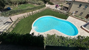 A swimming pool surrounded by a well-maintained lawn, with a view of the sea and hills in the background. - Holiday Apartment "La Rosa dei Venti" with Sea View, Shared Pool & Private Terrace (Santa Teresa Gallura)